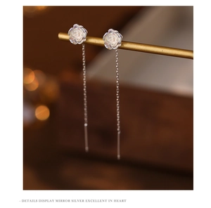 Macro detail of silver rose tassel earrings with iridescent white flower and long chain