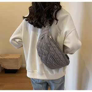 Rear view of a model wearing a grey quilted crossbody bag with minimalist styling