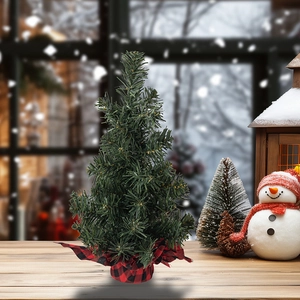 Mini green Christmas tree detail with classic red and black plaid burlap base on wood