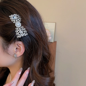 Detailed view of silver bow hair clip with pearls and rhinestones worn by a model