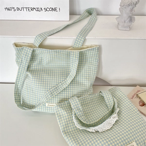 Detailed view of checkered canvas handbags with white lace trim in a lifestyle setting