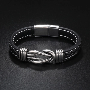 Detailed view of black braided leather bracelet with silver infinity knot magnetic clasp