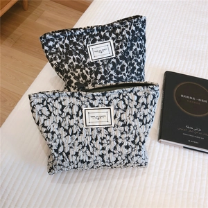 Close-up of black and white floral texture cosmetic bags with a zipper and label detail