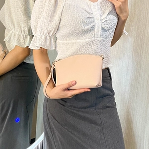 Pink lychee grain crossbody bag with shoulder strap shown in a mirror reflection