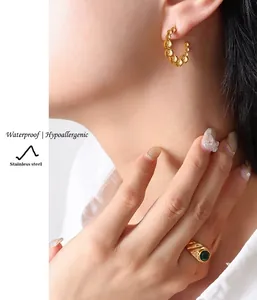 Vue détaillée des boucles d'oreilles perlées en C et de la bague émeraude en acier