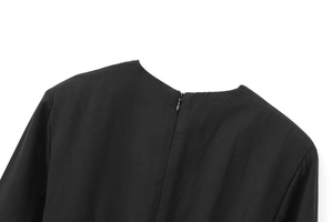 Détail de la fermeture éclair invisible au dos d'une robe noire à col en V texturée