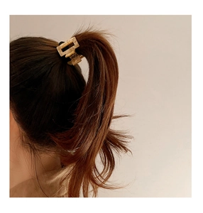 Detail view of a beige marble acetate square hair claw clip securing a ponytail hairstyle
