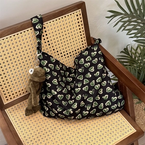 Close-up of black floral canvas tote bag with heart patterns on a vintage rattan chair