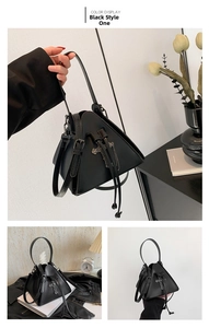 Detail view of black pyramid crossbody bag with cross chain and drawstring closure