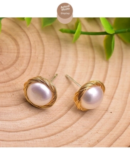Detailed view of natural pearl earrings with gold wire-wrapped nest design on wood