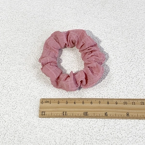 Pink floral scrunchie with pleated texture on white background with scale ruler