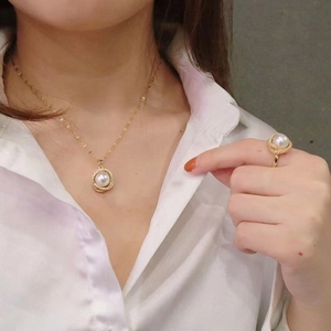 Elegant gold jewelry set with necklace and ring featuring white pearls on model