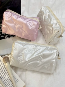 Quilted heart and bow makeup bags in pink and white with a metallic finish on a desk