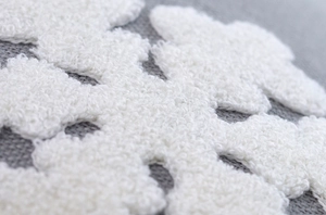 Macro detail of white snowflake embroidery texture on a grey cushion cover fabric