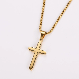 Gros plan détaillé d'un pendentif croix dorée avec une chaîne box sur un fond blanc