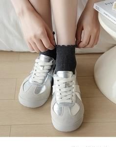 Close-up of silver metallic sneakers with grey suede panels and lace-edged ankle socks