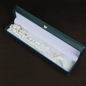 Beaded pearl necklace with crescent moon pendant in dark green luxury jewelry gift box