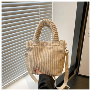 Detail of cream corduroy bucket bag showing soft texture, top handle, and button closure
