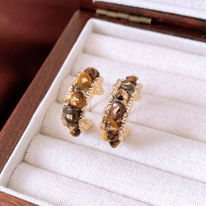 Nahaufnahme der goldenen Vintage-Creolen mit braunen Steinen auf weißem Samtbeutel