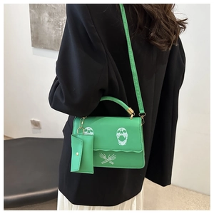 Rear view of a stylish green crossbody bag with white skull print and wavy flap edge