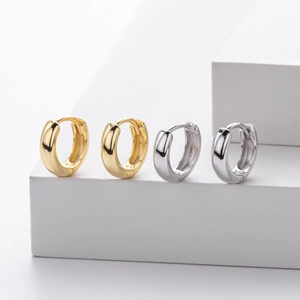 Detailed macro view of gold and silver S925 sterling silver hoop earrings on white steps