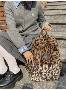 Zaino di peluche leopardato mostrato con un outfit casual all'aperto sui gradini