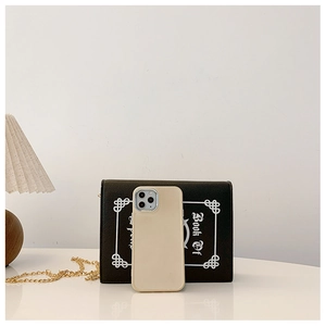 Close-up of beige minimalist phone case on a desk with a warm lamp and book props