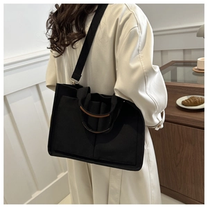 Détail d'un sac cabas en toile noire avec garniture en cuir brun et doubles poches
