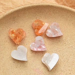Mini acetate heart hair claws in amber and cream marble textures on a round plate