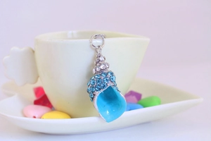 Macro shot of silver seashell keychain with sky blue rhinestones and enamel on ceramic cup