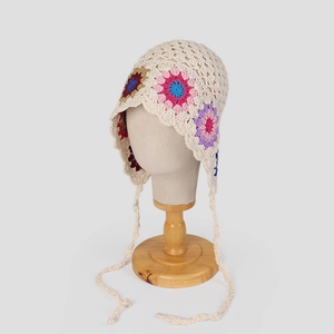 Detail of handmade crochet floral bonnet with pastel layered flowers and woven ties