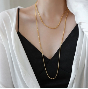 Detailed close-up of double-layered 18K gold-plated snake chain necklace on model