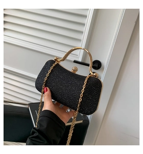 Close-up of black glitter evening bag featuring a gold metal handle and chain link strap