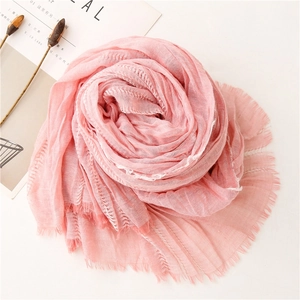 Detail of pink cotton-linen scarf showing soft pleated texture and fringe edges