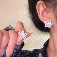 Detail of silver five-petal flower earrings with micro-pasted zircons on ear lobe