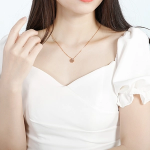 Detail of rose gold four-leaf clover necklace pendant on model with soft lighting