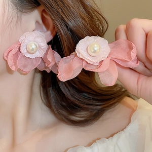 Detail of pink mesh flower earrings with central pearl showing fabric texture on ear
