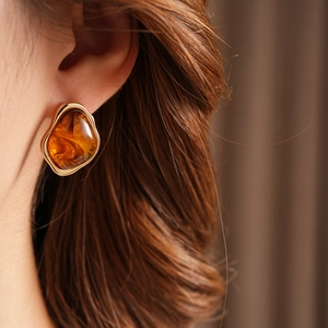 Close-up of vintage geometric amber resin earrings with a textured golden metal frame