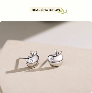 Macro shot of silver apple stud earrings with a tiny sparkling cubic zirconia stone