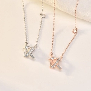 Detail of silver and rose gold starburst necklaces with crystal paved letter K pendant