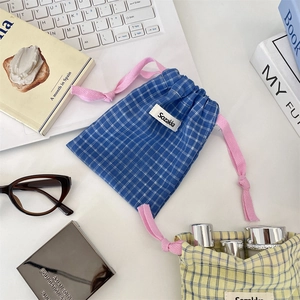 Blue and yellow plaid drawstring storage bags for cosmetics on a white desk