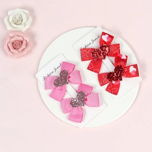Detail of red and pink heart bow hair clips on display card with floral decoration