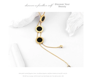 Detailed macro view of gold lariat snake chain necklace with roman numerals and black inlays