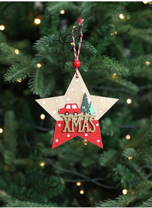 Wooden Christmas star ornament with XMAS text hanging on a warm lit festive tree