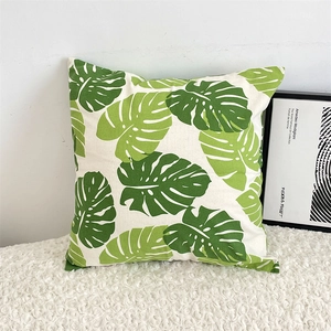 Close-up of green monstera leaf print on square cotton linen throw pillow cover