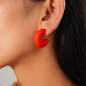 Close-up of red acrylic matte C-shaped hoop earring worn on a model's ear lobe