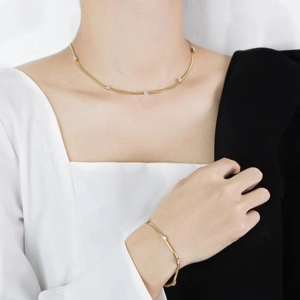 Detail of 18K gold-plated chain set with rectangular white zircon stones on model