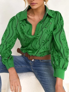 Detail of green blouse with floral embroidery, hollow-out design and puff sleeves