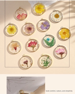 Macro view of handmade resin pendants with real dried flowers and gold foil in metal rings