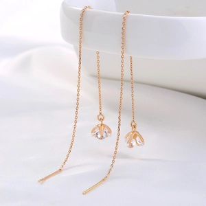 Detail of long gold tassel earrings with sparkling zircons hanging on a white ceramic bowl